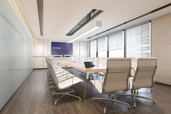 Modern conference room with long table, white chairs, and wall-mounted display screen